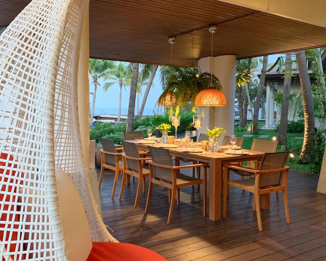 Ground floor: the covered terrace dining table set for dinner, sea beyond