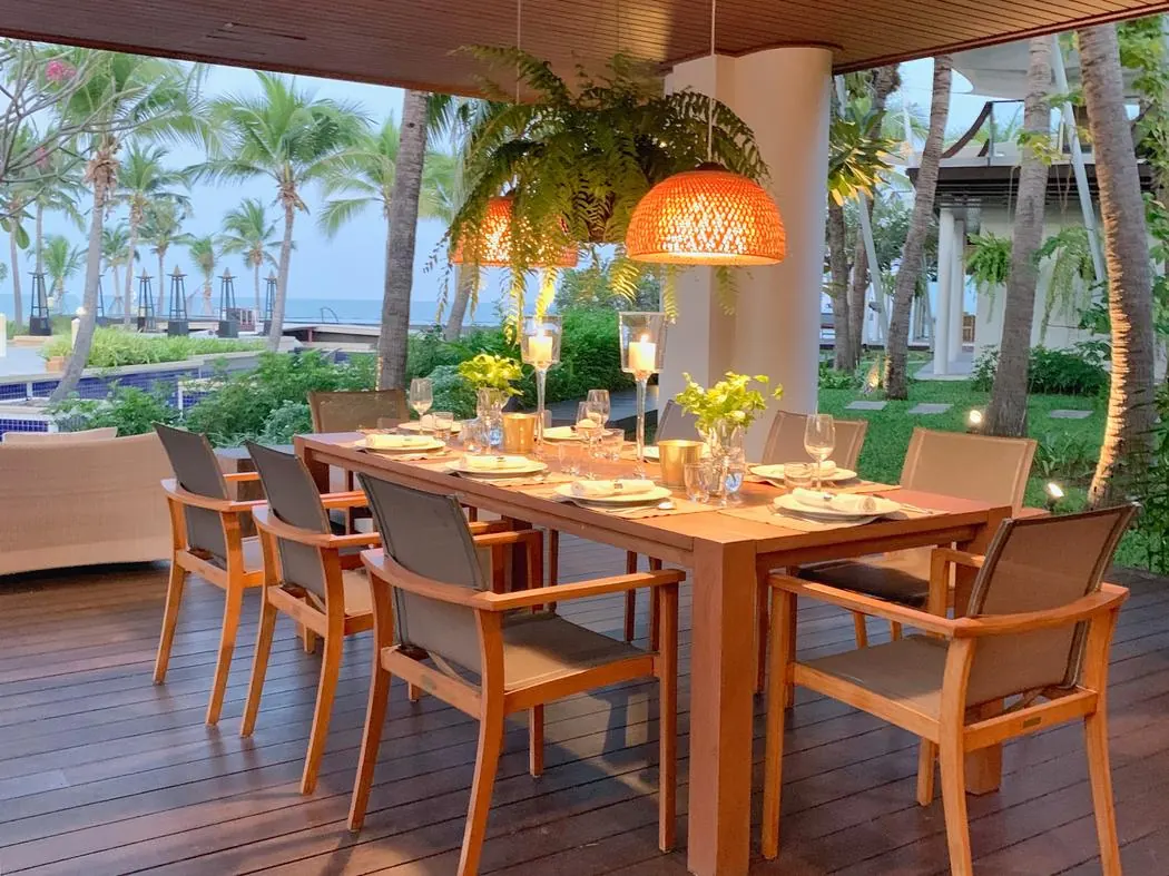 Ground floor: the terrace dining table set for dinner at dusk, lanterns lit and the sea beyond