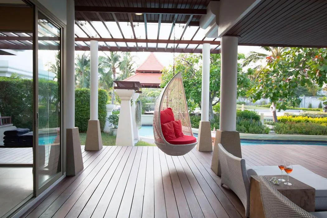 Ground floor: covered outdoor lounge with hanging chair beside the pool