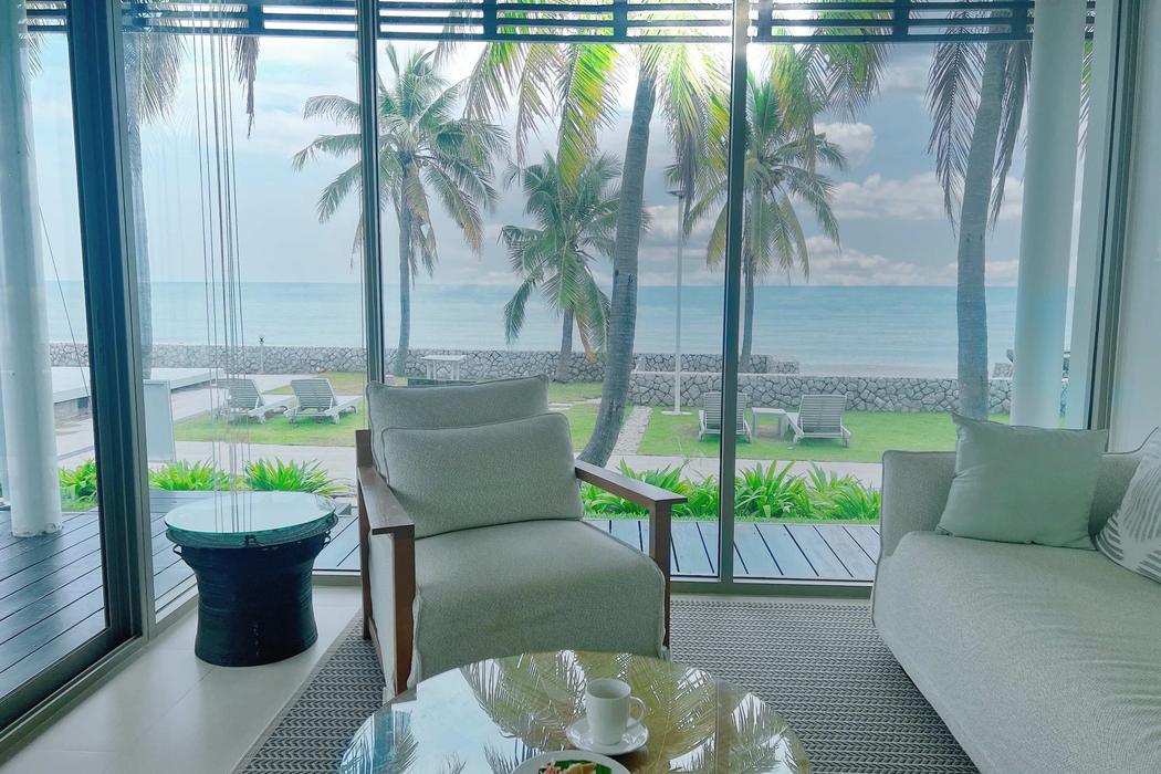 The living room corner, full height glass onto the palms and the sea