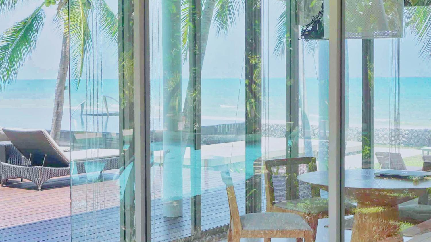 The full height glass wall of the Beachfront Pavilion, terrace and sea beyond