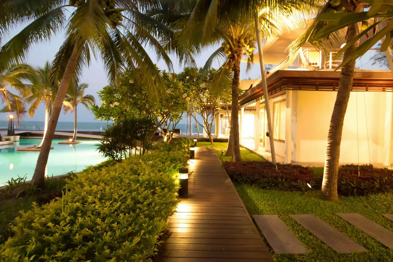 Lit timber walkway between the pavilions at dawn