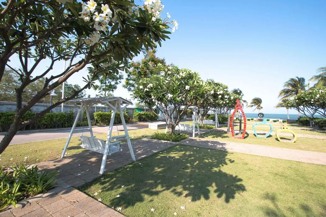 A swing seat under the frangipani beside the playground